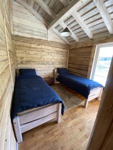 a bedroom with two beds in a wooden cabin at Pelėdų Namelis in Šlaveitai