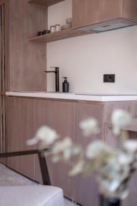Bloom Suites في بريشتيني: مطبخ مع دواليب خشبية وطاولة زجاجية