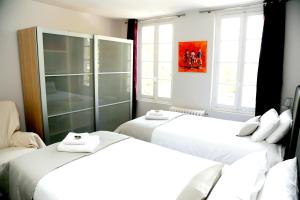 Duas camas brancas num quarto com janelas em Appartement d'une chambre avec wifi a Cognac em Cognac