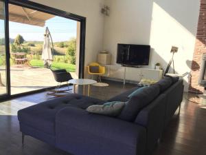 ein blaues Sofa im Wohnzimmer mit Glasschiebetür in der Unterkunft grande villa, piscine chauffée, proche Bordeaux in Lignan-de-Bordeaux