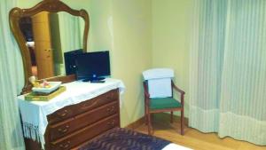 a bedroom with a dresser with a mirror and a chair at Elegant House in Pontevedra + Private Pool in Rífrío