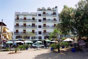 a large white building with umbrellas in front of it at Elena Beach in Chania