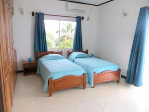 2 Betten in einem Zimmer mit blauen Vorhängen und einem Fenster in der Unterkunft 2 bedrooms villa with sea view enclosed garden and wifi at Victoria Zig Zag Ward 6 km away from the beach in Victoria