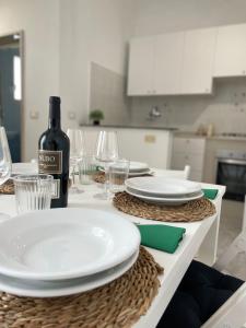 un tavolo con piatti bianchi e una bottiglia di vino di PIACENTINI - Apulia Home a San Pietro in Bevagna