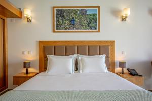 um quarto com uma grande cama branca e 2 candeeiros em Hotel Rural Brícia Du Mar em Ferragudo