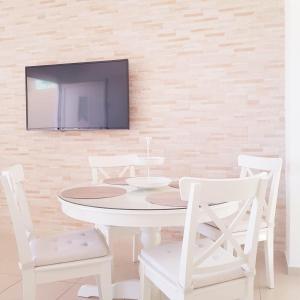 a white table and chairs with a tv on a wall at Katy's Luxury Apartments in Kavros