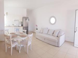 a living room with a white couch and a table and chairs at Katy's Luxury Apartments in Kavros