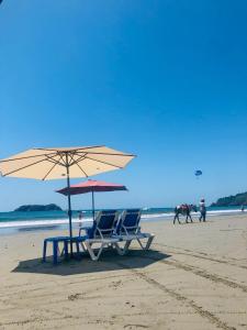 a table and two chairs and an umbrella on a beach at Hospedaje Colibri in Manuel Antonio