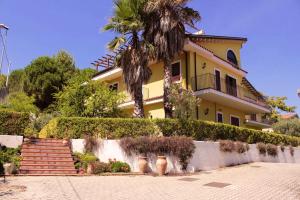 una casa amarilla con una palmera y escaleras en 2 bedrooms appartement with enclosed garden and wifi at Nicolosi, en Nicolosi