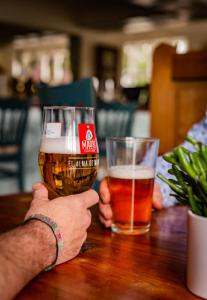 een man die een glas bier omhoog houdt bij The Cricketers Inn in Petersfield