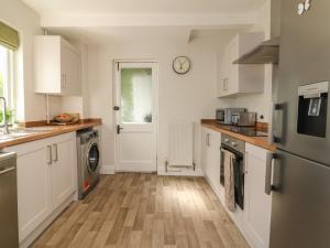 a kitchen with white cabinets and a washer and dryer at Myrtle House in Ilfracombe