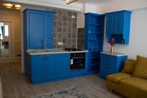 eine Küche mit blauen Schränken und einem Sofa in der Unterkunft Blue Joy Bukovina Aparthotel in Suceava