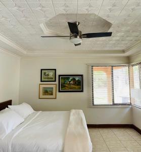 a bedroom with a white bed and a ceiling fan at Casa Mano de Tigre in Potrerillos