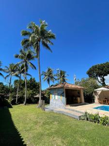 a house with a palm tree next to a pool at Céu Azul Pousada in Arraial d'Ajuda