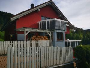 a red house with a white fence in front of it at Ferienwohnung Am Rubersbach in Hornberg