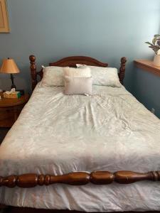 een groot bed met een houten hoofdeinde en witte lakens bij Pershing, Heights, 102 in New Kensington