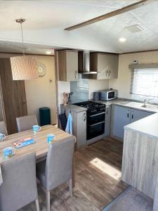 a kitchen with a wooden table with chairs and a dining room at GOOD SHIP LOLLIPOP LODGE - Birchington-on-Sea - 6 mins drive to Minnis Bay Beach in Kent