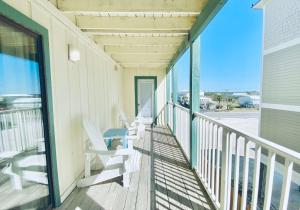 une terrasse couverte avec des chaises blanches et une table. dans l'établissement Sundial 2C by ALBVR - Great Views - Great Location and Amenities, à Gulf Shores