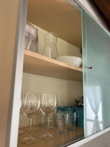 una fila de copas de vino sentadas en un estante en Intero Appartamento Ristrutturato - Voghera, en Voghera