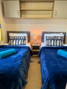 two beds in a room with blue sheets at GOOD SHIP LOLLIPOP LODGE - Birchington-on-Sea - 6 mins drive to Minnis Bay Beach in Kent