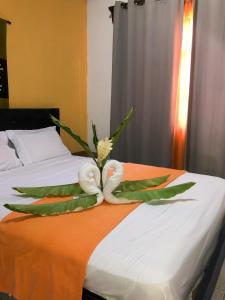 a hotel room with a bed with towels and a flower at Hospedaje Colibri in Manuel Antonio