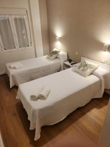 twee bedden in een hotelkamer met handdoeken erop bij Hostal Restaurante CASA FRAN in La Pueblanueva