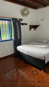 une chambre avec un lit dans une pièce avec une fenêtre dans l'établissement Cabaña El Arenal San Rafael Antioquía, à San Rafael