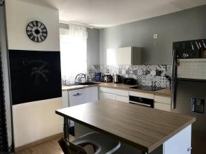 a kitchen with a table and a clock on the wall at Appartement cosy - vue mer in Le Robert