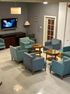 a waiting room with chairs and tables and a tv at Petra Town Check-Inn in Wadi Musa