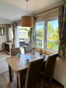 a dining room table with chairs and a large window at GOOD SHIP LOLLIPOP LODGE - Birchington-on-Sea - 6 mins drive to Minnis Bay Beach in Kent