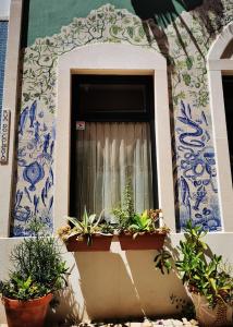 a window with potted plants in front of a building at Charming Portuguese style apartment, for rent "Vida à Portuguesa", "Fruta or Polvo" Alojamento Local in Portimão