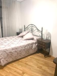 a bedroom with a bed with a wooden floor and a table at 2 bedrooms apartement with city view balcony and wifi at Ciudad Real in Ciudad Real