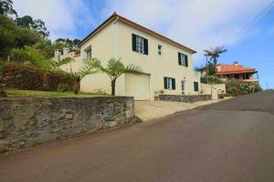 Biały dom z kamienną ścianą obok ulicy w obiekcie Elegant Apartment in Levada Grande + Terrace + 120 m² w mieście Lanceiros