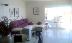 a living room with a purple couch and a table at 3 bedrooms apartement with sea view shared pool and furnished garden at Aguilas in Águilas
