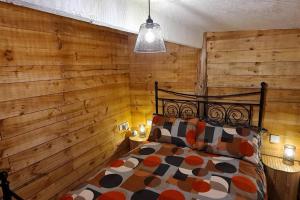 a bedroom with a wooden wall with a bed and a lamp at The Wendy house in Parkend