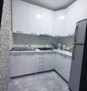 La cuisine est équipée de placards blancs, d'un évier et d'un réfrigérateur. dans l'établissement White House In Borjomi, à Bordjomi
