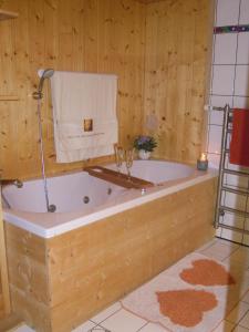 bañera en una habitación con pared de madera en Sonnenhof, en Schröcken