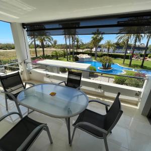 einen Glastisch und Stühle auf einem Balkon mit Poolblick in der Unterkunft Torredembarra in Torredembarra