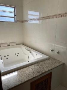 een witte badkamer met een bad en een douche bij Pousada Cabana in Avaré