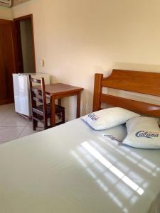 een slaapkamer met een bed met 2 kussens en een tafel bij Pousada Cabana in Avaré