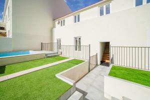 un patio con césped verde en un edificio blanco en Vila Lopes, en Lisboa