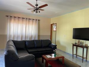 a living room with a black couch and a ceiling fan at Pousada Cabana in Avaré