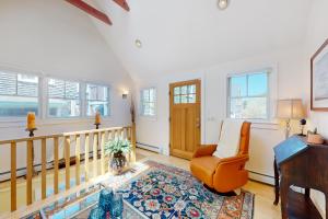 a living room with an orange chair and a staircase at Beech Tree Retreat in Provincetown