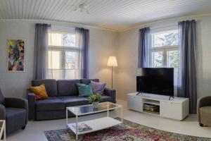 a living room with a couch and a tv at Villa Moisio - puutaloidylliä Salon keskustassa in Salo