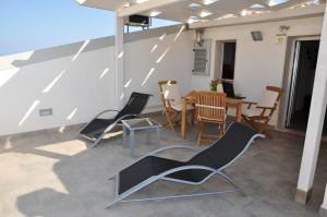 un patio avec des chaises et une table sur le toit dans l'établissement One bedroom appartement at Punta Secca 100 m away from the beach with sea view terrace and wifi, à Punta Secca