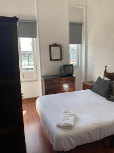 a bedroom with a bed and a television and two windows at Hospedaria Porto in Porto