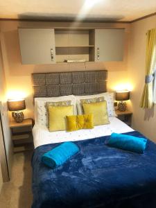 a bedroom with a large bed with blue and yellow pillows at GOOD SHIP LOLLIPOP LODGE - Birchington-on-Sea - 6 mins drive to Minnis Bay Beach in Kent