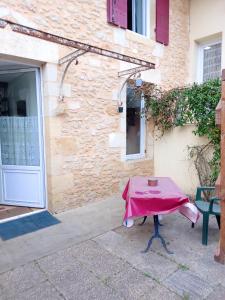 einem Tisch mit einem rosa Tischtuch vor einem Gebäude in der Unterkunft Studio avec jardin clos et wifi a Langon in Langon