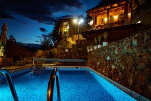 a swimming pool at night with lights on a building at Safari Village Velingrad in Velingrad