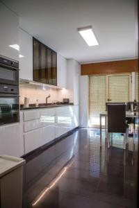 a large kitchen with white cabinets and a table at 5 bedrooms villa with city view private pool and jacuzzi at Porto in Porto